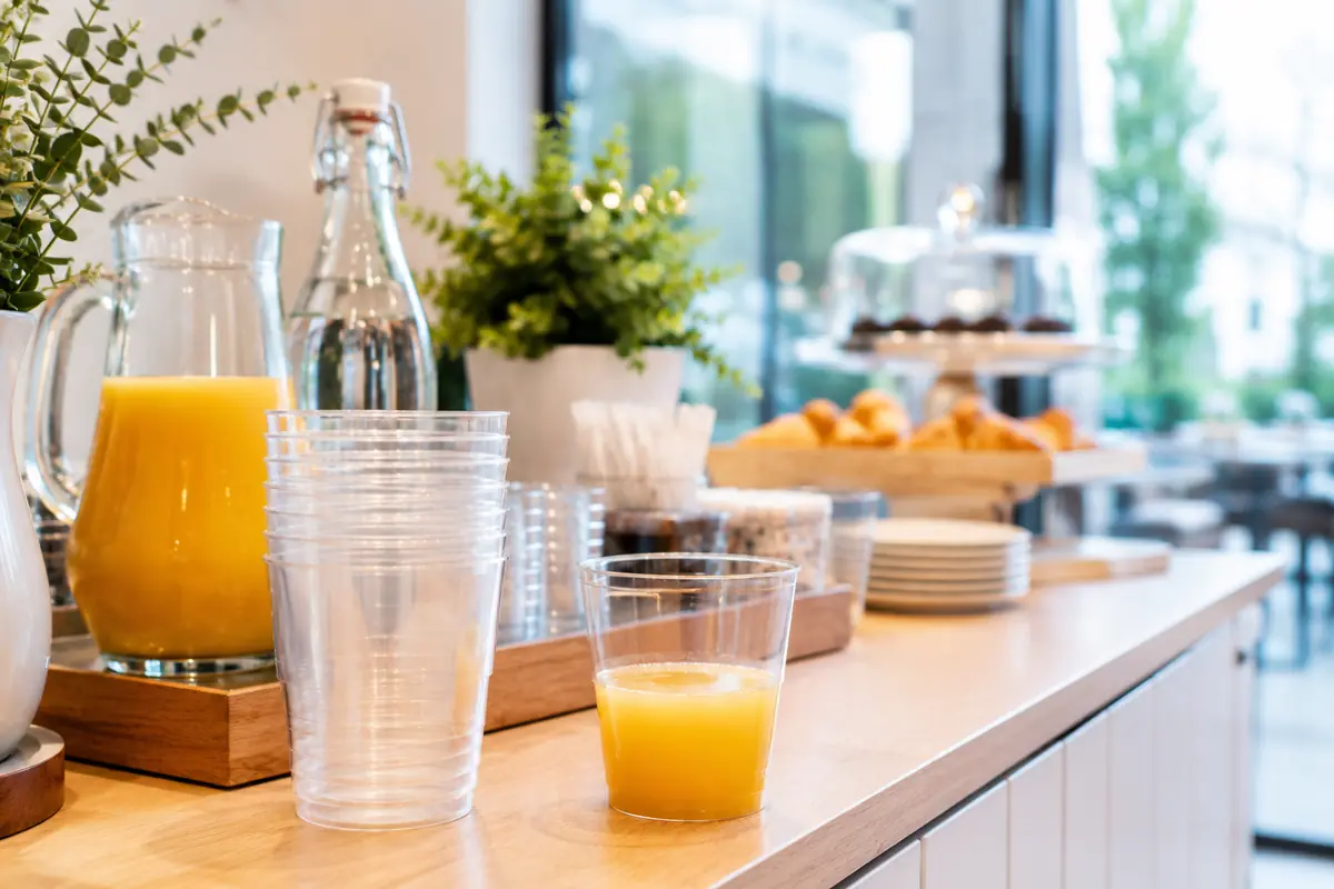 Primo piano di un buffet colazione in hotel con succhi di frutta in bicchieri compostabili